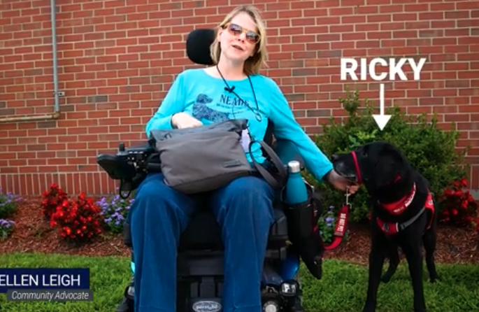 woman in wheelchair with black service dog at her side